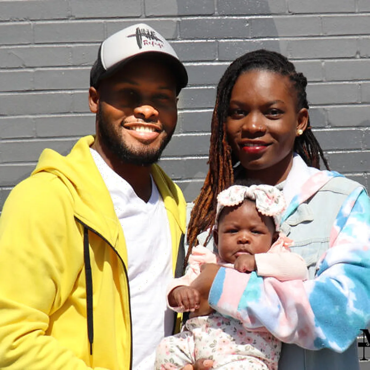 Atuhaire Gavin with his wife and baby outside The Refuge.