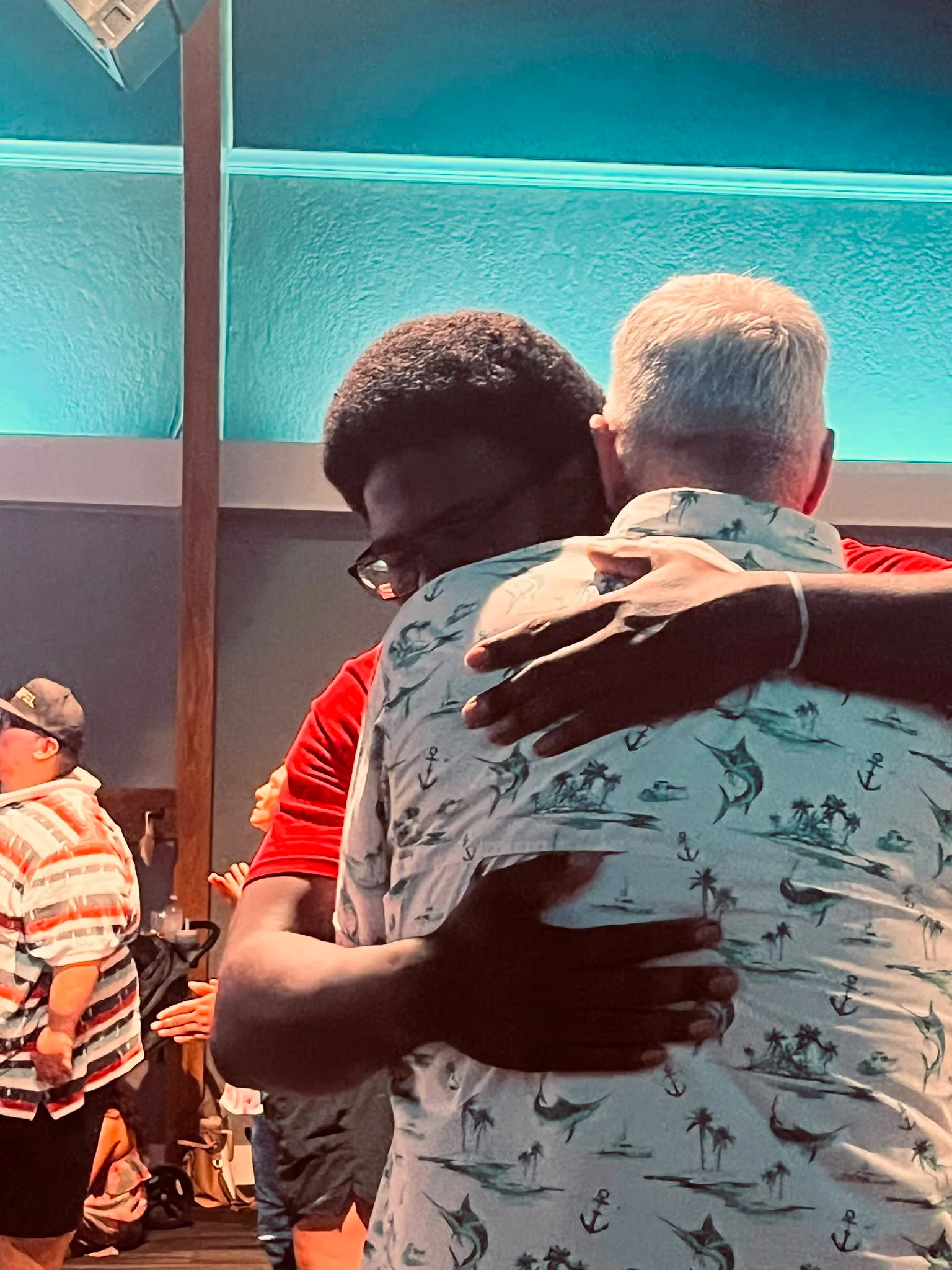 Two men sharing a warm embrace during a Refuge gathering.