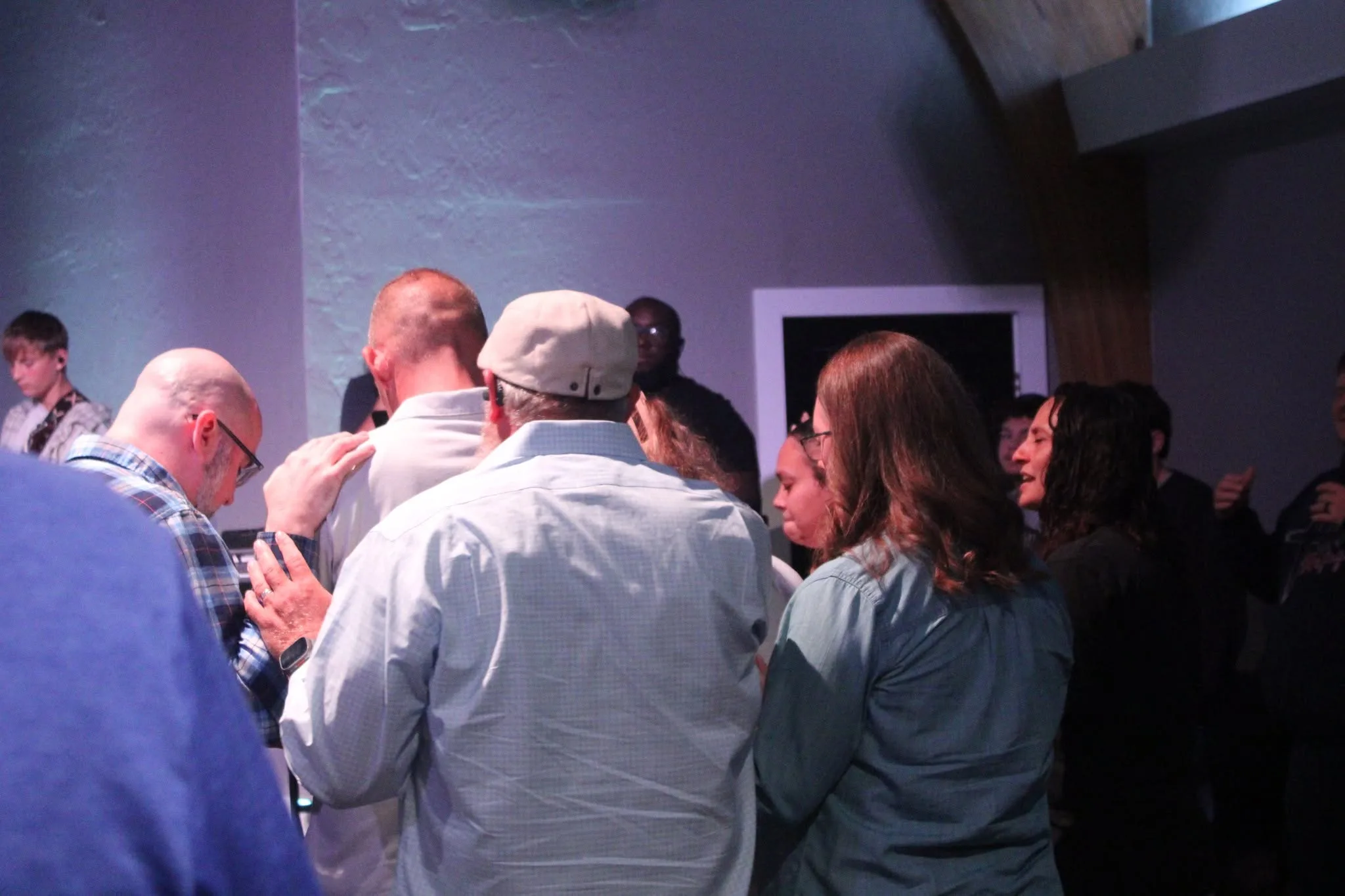 A small group gathered shoulder to shoulder in prayer at The Refuge.