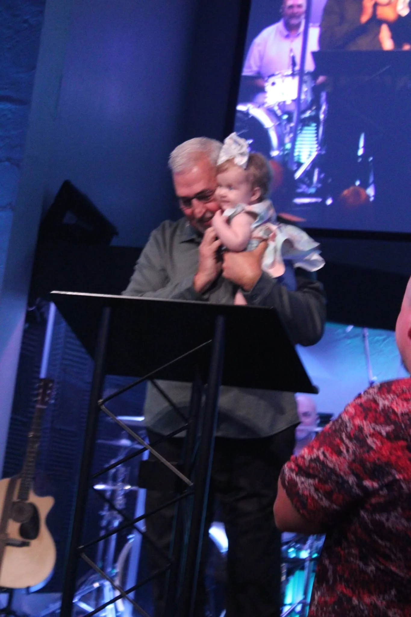 Pastor Larry holding a child during a dedication at The Refuge.