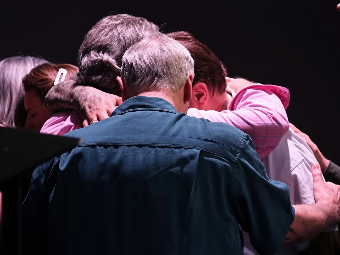 A group gathered in a close embrace during a Refuge gathering.