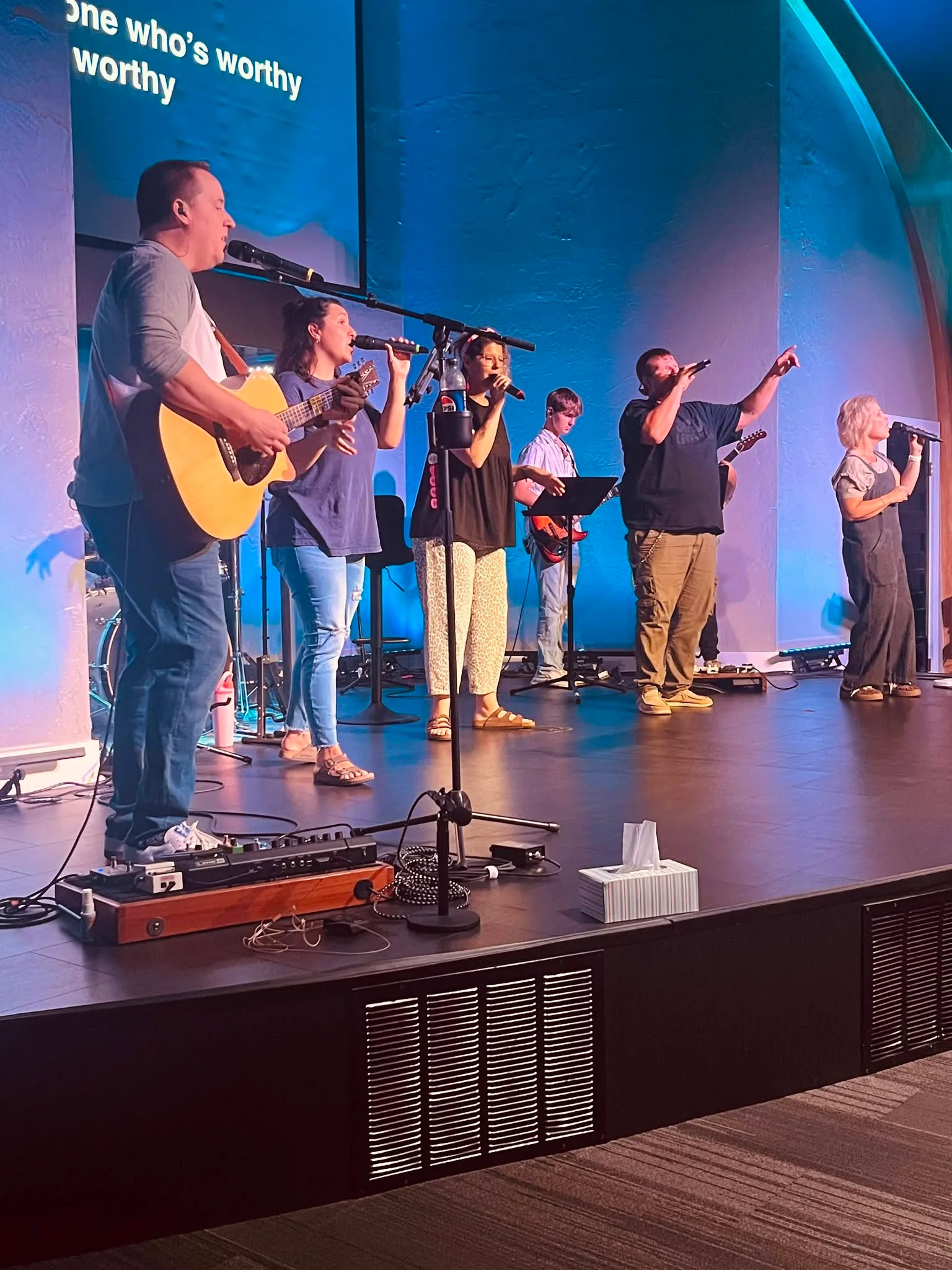 The worship team leading beneath blue sanctuary light.