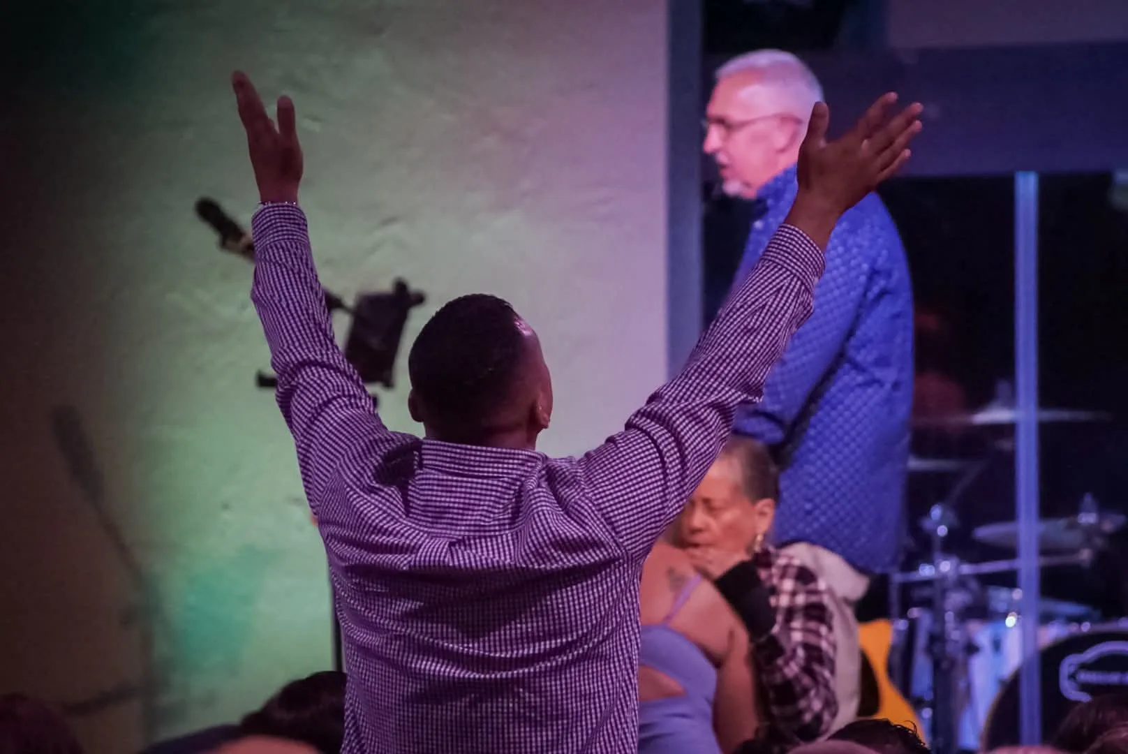 A man with arms raised in worship during a Refuge service.